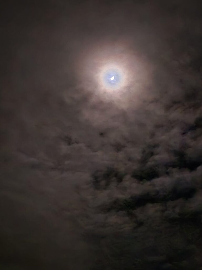 Lune entourée d'un halo lumineux à travers les nuages nocturnes
